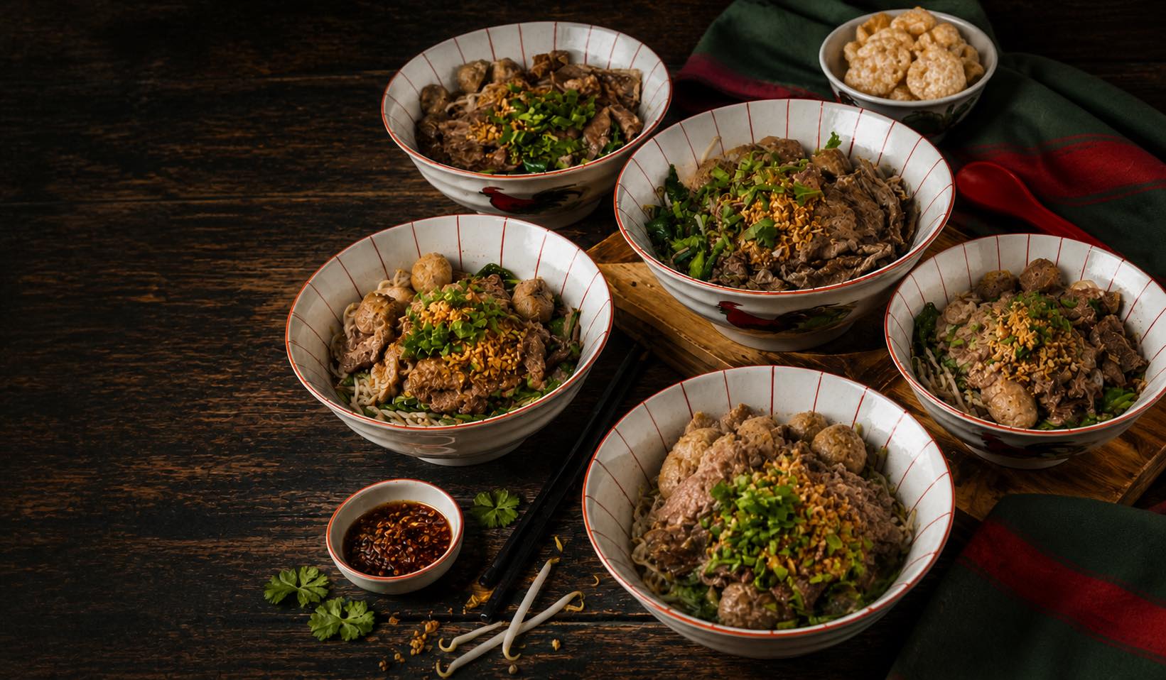 Five bowls of Teow Ruer beef boat noodles on a dark market table