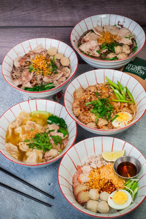 Five small noodle bowls crowding a table, each with a different topping