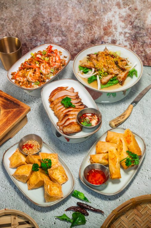 Plates to share: fried tofu, spring rolls, sliced BBQ pork, a noodle bowl and a spicy salad